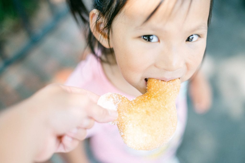 Little girl eating mickey mouse beignet at Disneyland | Photo taken by Amy Huang Photography | A San Diego Photographer
