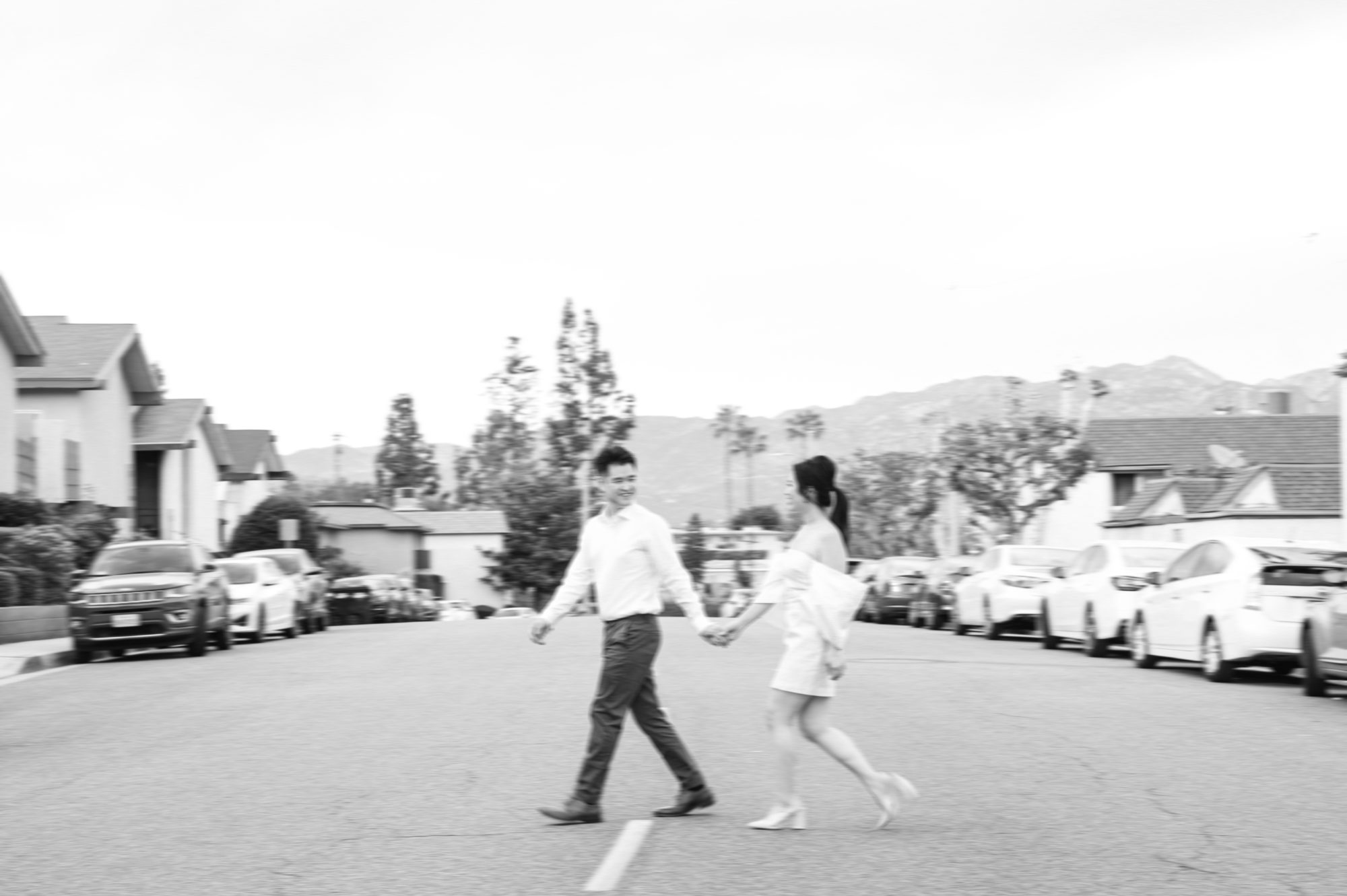A bride and a groom celebrating in a Los Angeles Engagment Session, they are walking across the street holding hands.