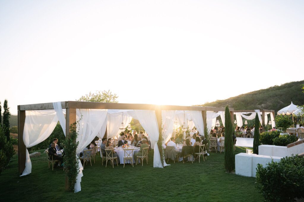 Outdoor reception at Jeune Perche, a European-inspired San Diego wedding venue showcasing elegant drapery, natural greenery, and stylish table settings under the golden sunset.